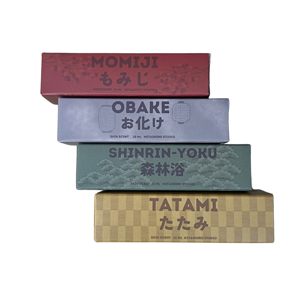 Stack of four roll on perfume boxes with different designs and text on a white background