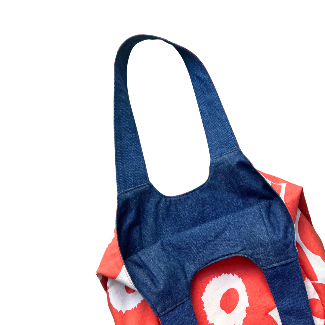 Inside denim lining of orange and white floral bag on a white background